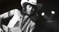 Willie Nelson playing guitar in black and white